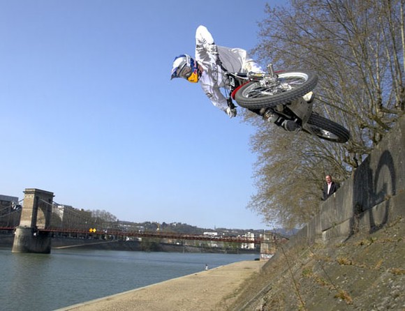 Photo de Julien Dupont qui saute en TrialX sur le quai d'un rivière