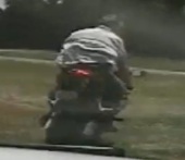 Un motard sans casque en sportive dans un champs tente d'échapper à la police